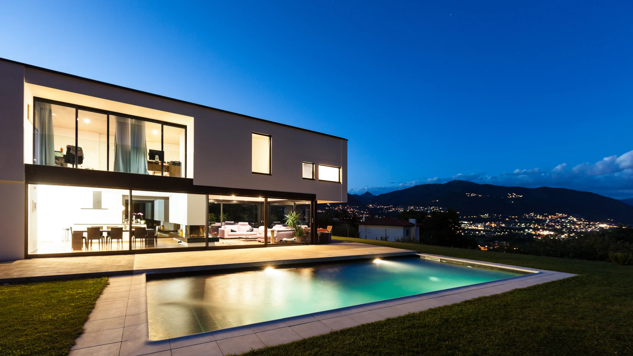 Illuminated contemporary villa and reflecting pool at dusk